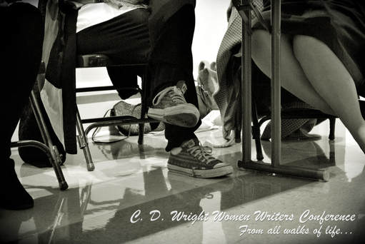 Black and white image of two sets of legs under a table. One pair in jeans and sneakers; one pair in skirt, hose, and pumps. Caption: C.D. Wright Women Writers Conference / From all walks of life...